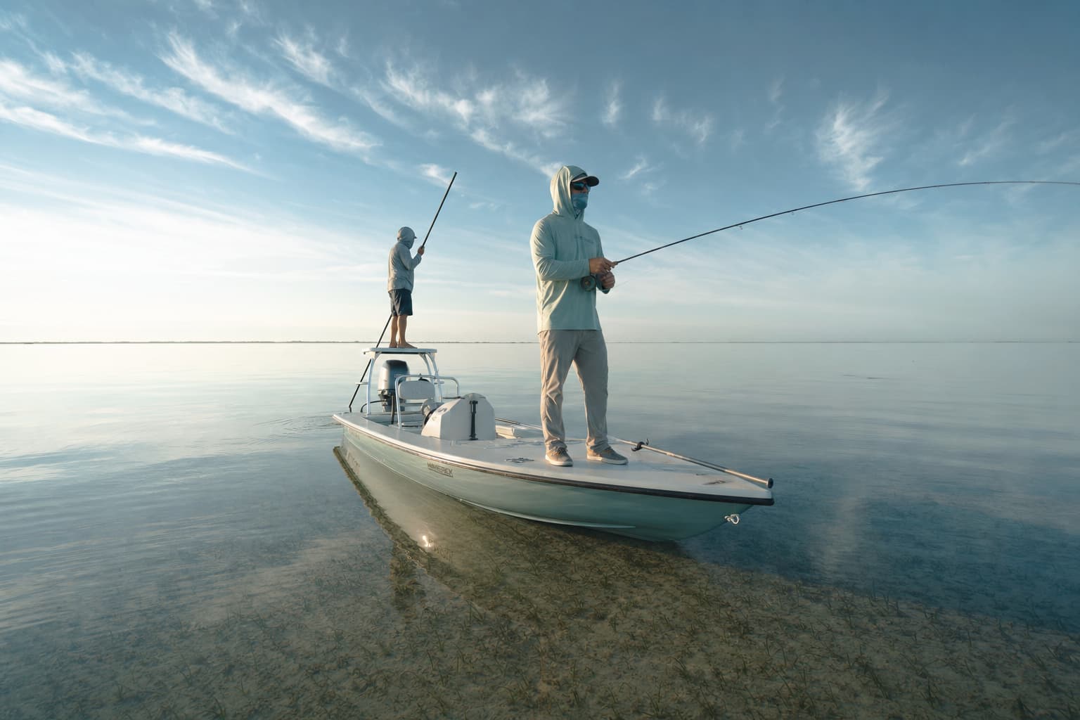 Anglers poling a skiff across the Laguna Madre flats at sunrise